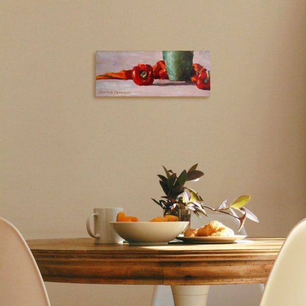 Oil painting of red peppers, a green copper vase juxtaposed with an orange fabric all arranged on a grey background displayed on a wall.