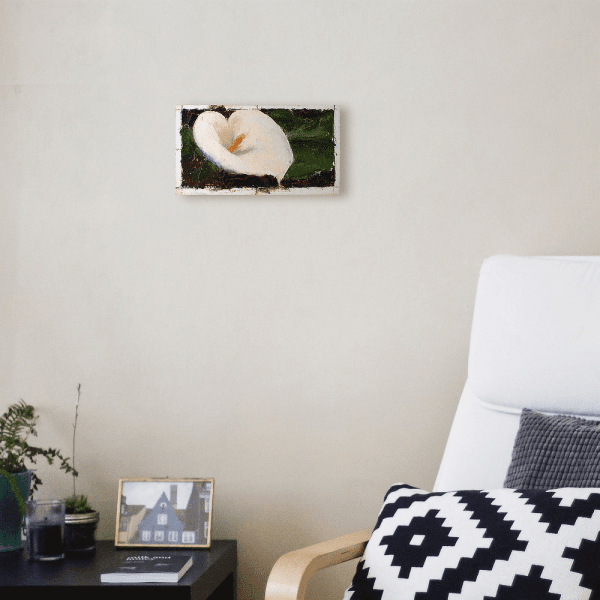 Oil painting of a white calla lily with yellow pistol tightly framed in warm dark brown background displayed on a wall.