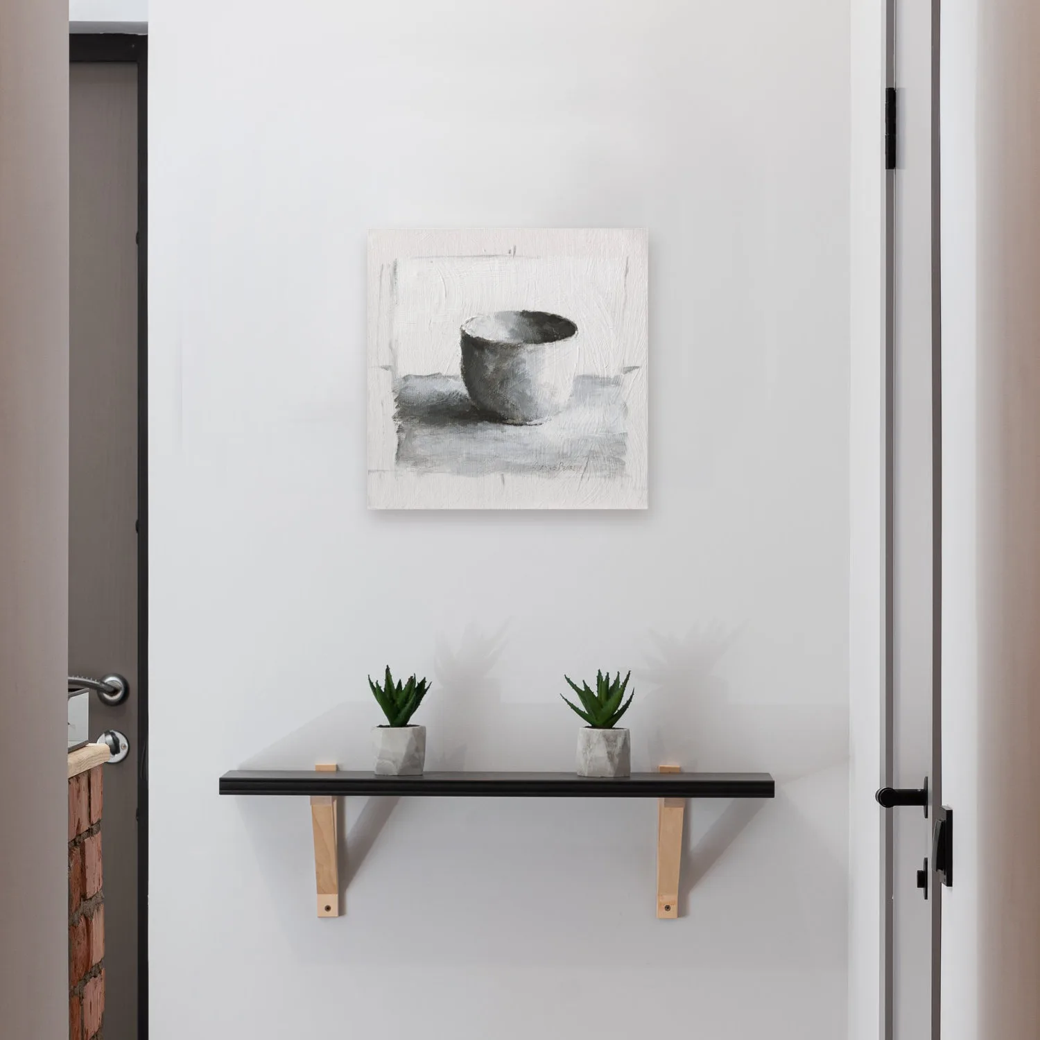 Monochromatic oil painting of a white cup on a white background with black and grey shadows displayed on a wall.