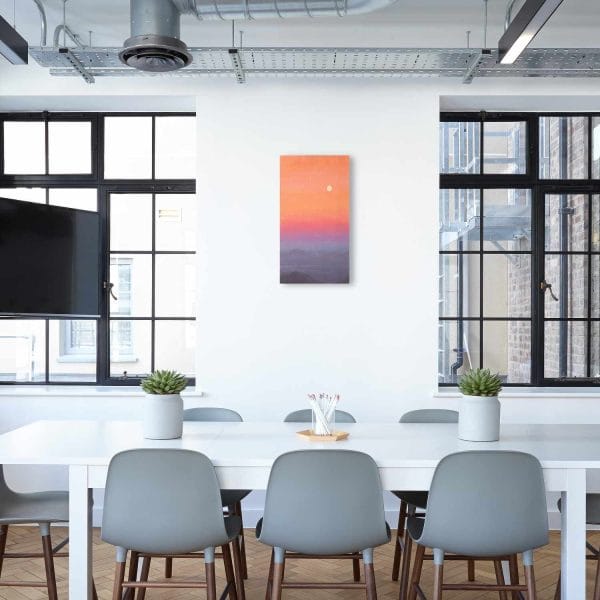 An oil painting of a full moon above the horizon and distance mountains in a vibrant, colorful sky at dusk as displayed on an interior wall.