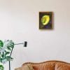 An oil painting of a yellow calla lily, placed against a warm green and dark violet background as displayed on an interior wall.