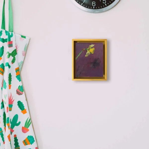 An oil painting of a bright yellow daffodil casting a shadow on a dark purple background as displayed on an interior wall.