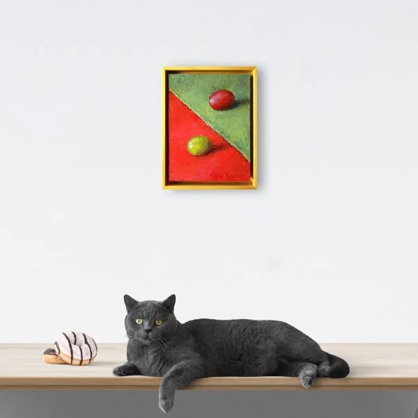 An oil painting of a green grape on red fabric juxtaposed with a red grape on a green fabric as displayed on an interior wall.