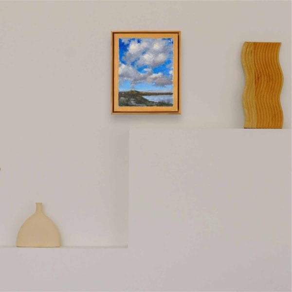 An oil painting of white puffy clouds in a deep blue sky rising above the Cerro Pedernal, near Ghost Ranch, Abiquiu, almost seem as if the clouds emerge from this ancient volcanic formation in this landscape of water, mountains, clouds, and sky as displayed on an interior wall.