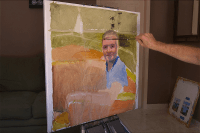 Canvas, paint and brushes used in creating a portrait painting of a young man on boat.