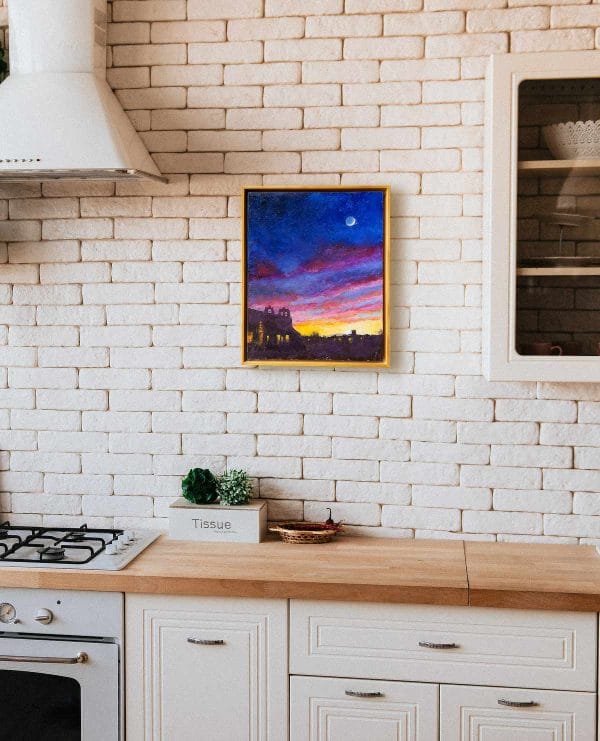 Oil painting of the moon in a yellow, red, and violet evening sky above the silhouettes of buildings around the plaza of Taos, New Mexico, displayed on a wall.