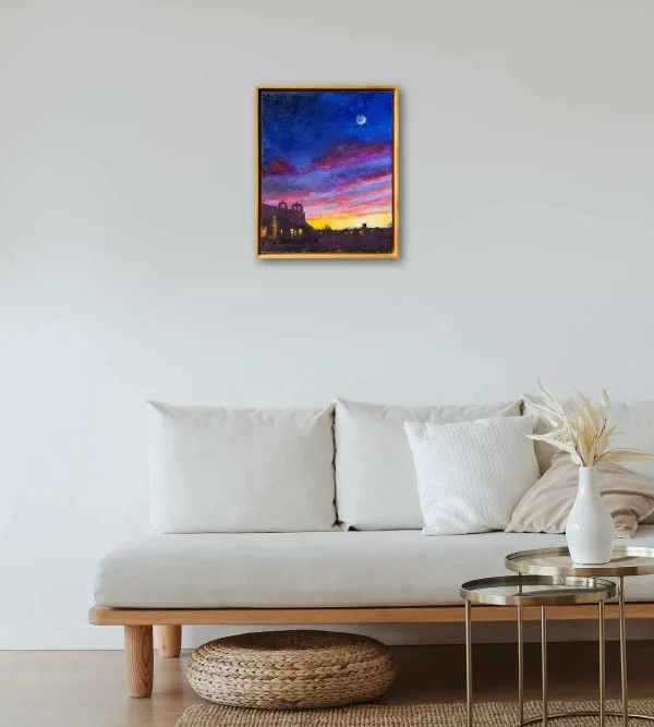Oil painting of the moon in a yellow, red, and violet evening sky above the silhouettes of buildings around the plaza of Taos, New Mexico, displayed on a wall.