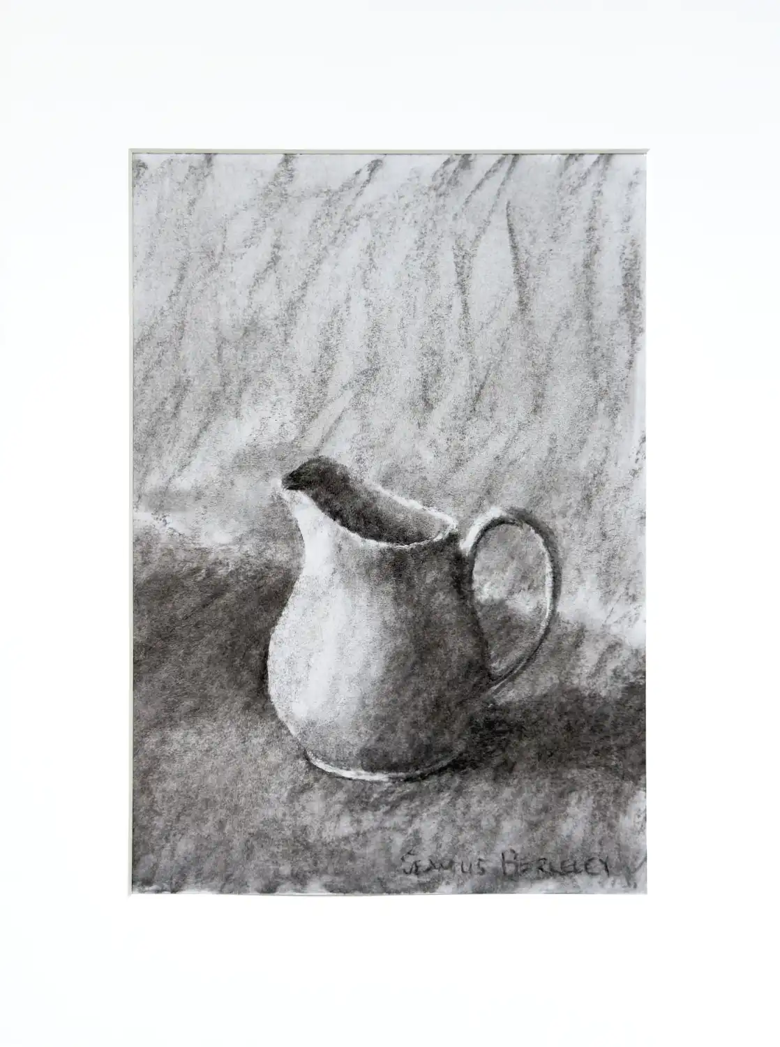 A charcoal drawing of a white pitcher with a handle on the right placed on a grey fabric.